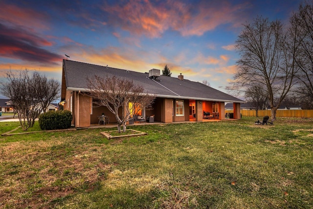 back house at dusk featuring a patio area, a yard, and cooling unit