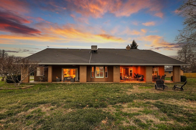 back house at dusk featuring a lawn, a patio area, and an outdoor fire pit