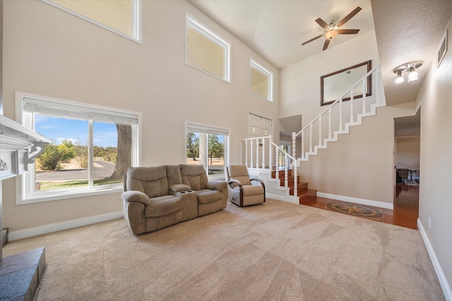 carpeted living room with a high ceiling, ceiling fan, and a textured ceiling