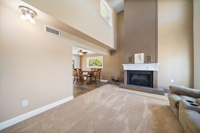 carpeted living room featuring ceiling fan and a tile fireplace