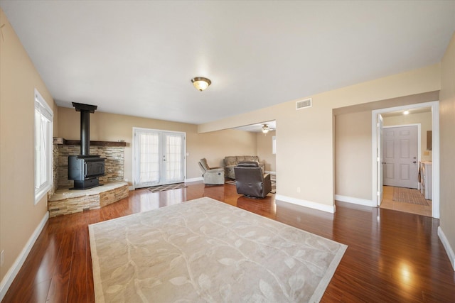 living room featuring ceiling fan, dark wood-type flooring, a wood stove, and french doors