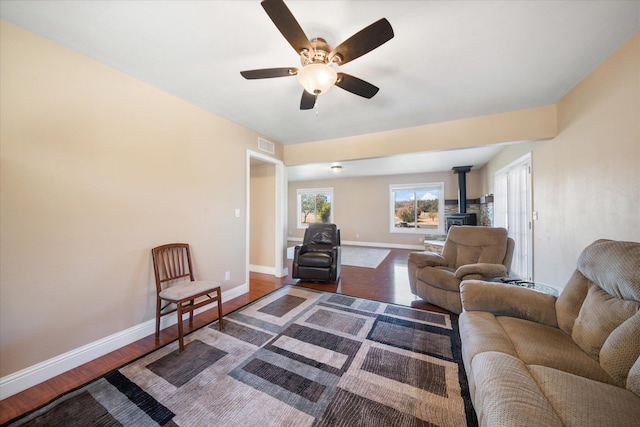 living room featuring ceiling fan, wood-type flooring, and a wood stove