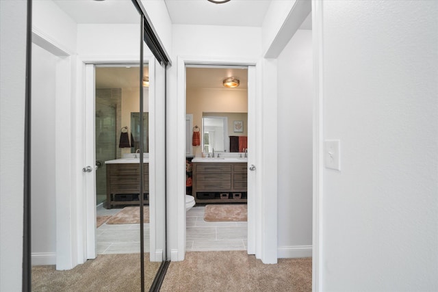 corridor with light carpet and sink