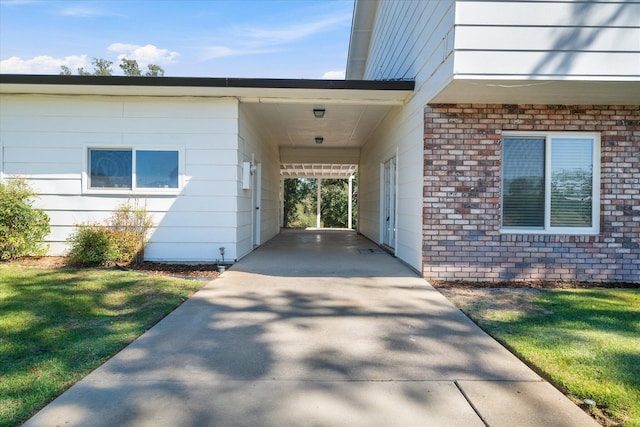 view of exterior entry with a lawn and a carport