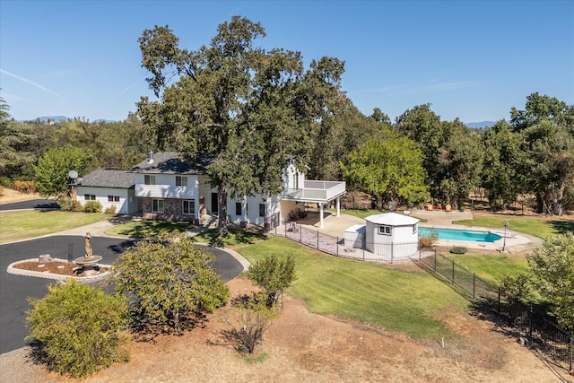 rear view of house featuring a fenced in pool and a lawn