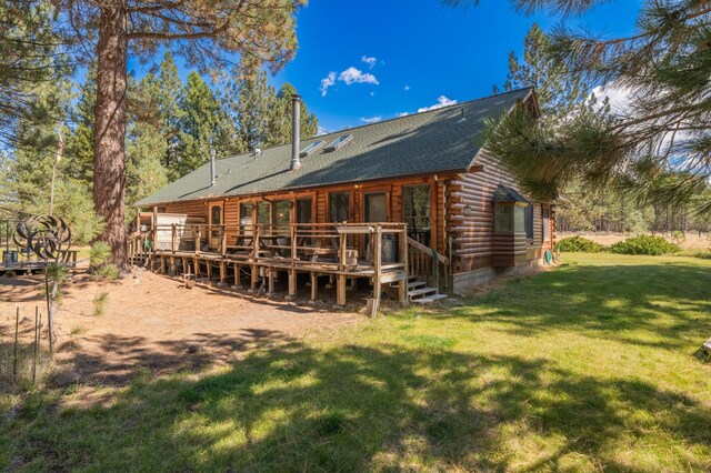 rear view of property featuring a deck and a lawn