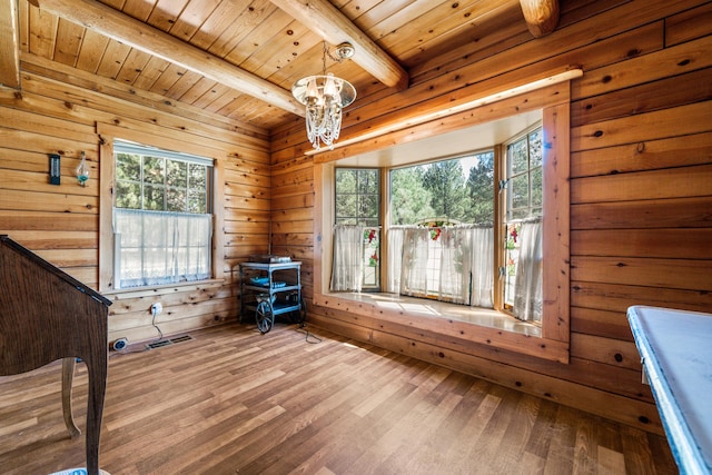 unfurnished bedroom with wood ceiling, wood-type flooring, a chandelier, beam ceiling, and wood walls