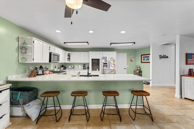 kitchen featuring sink, a breakfast bar area, white cabinets, kitchen peninsula, and appliances with stainless steel finishes