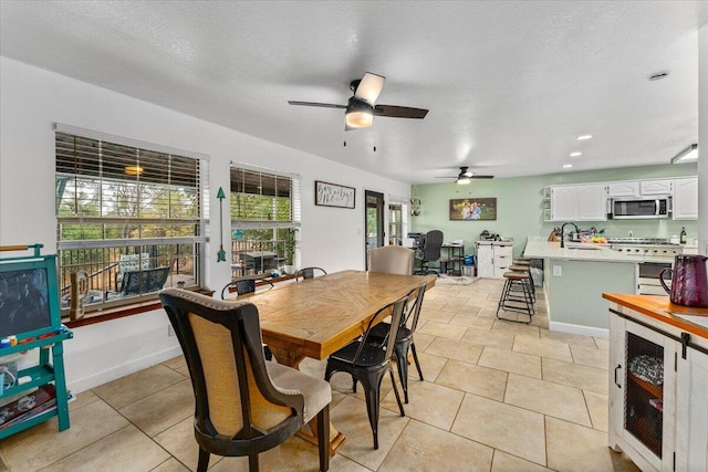 tiled dining space with beverage cooler, ceiling fan, and a textured ceiling