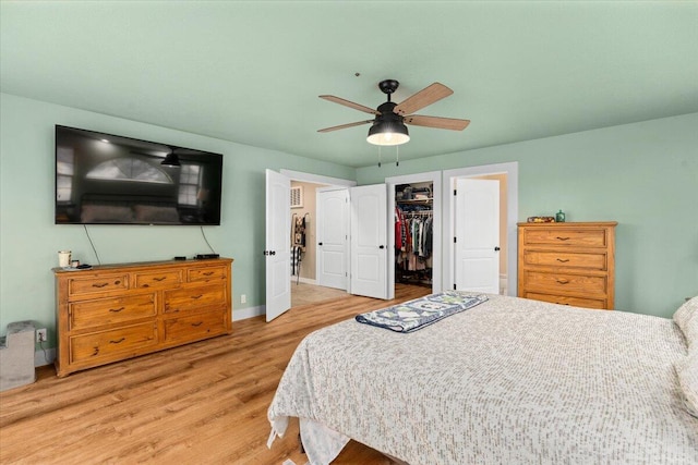 bedroom with a closet, light hardwood / wood-style floors, ceiling fan, and a walk in closet