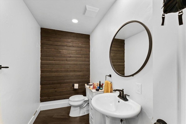 bathroom featuring sink, wooden walls, toilet, and hardwood / wood-style flooring