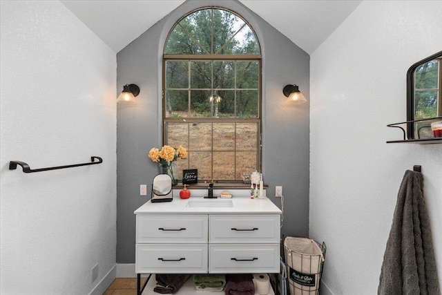 bathroom featuring tile patterned flooring, vaulted ceiling, and vanity