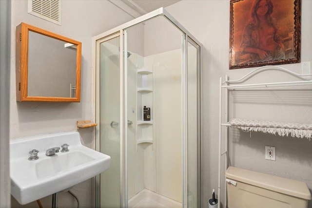 bathroom featuring toilet, sink, and a shower with shower door