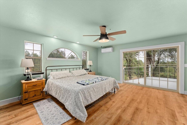 bedroom with multiple windows, ceiling fan, a wall mounted AC, and light hardwood / wood-style flooring