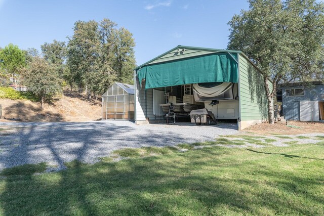 view of outdoor structure with a carport and a lawn