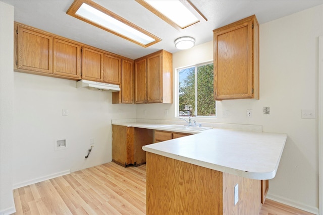 kitchen featuring kitchen peninsula, light hardwood / wood-style floors, and sink