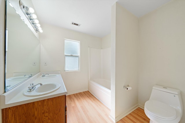 full bathroom with vanity, hardwood / wood-style flooring, shower / tub combination, and toilet