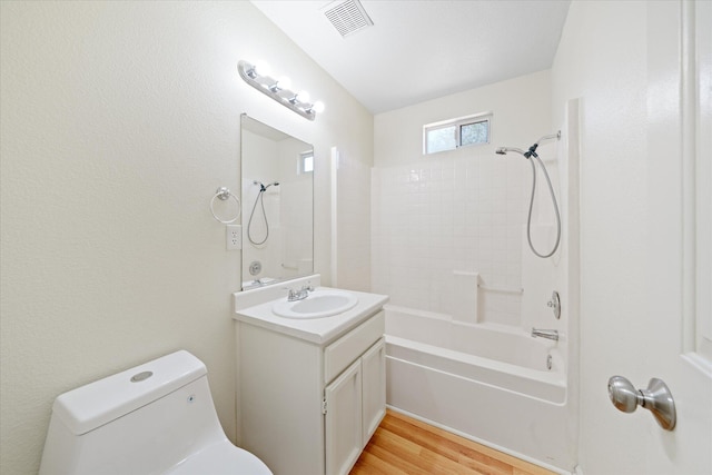 full bathroom with hardwood / wood-style floors, tiled shower / bath combo, vanity, and toilet