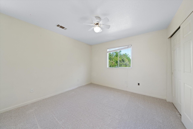 unfurnished bedroom featuring light carpet, a closet, and ceiling fan