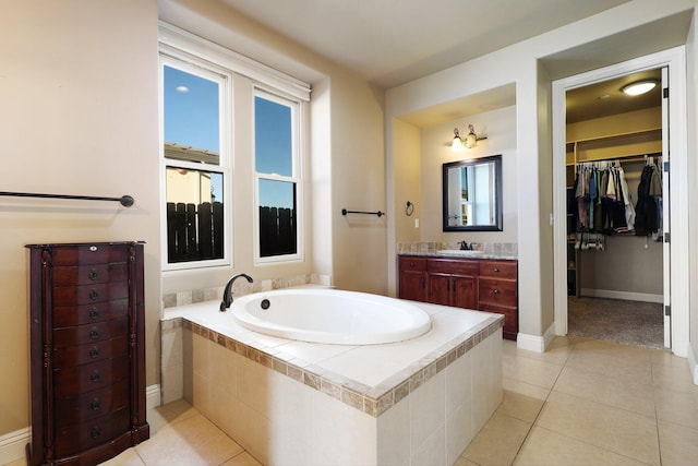 bathroom with tile patterned flooring, vanity, and a relaxing tiled tub