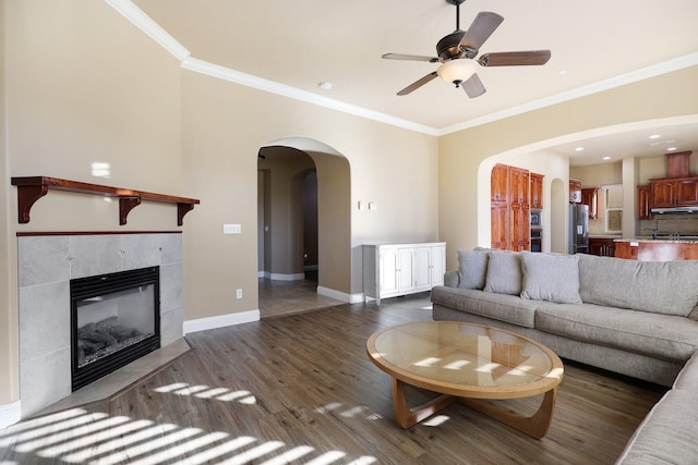 unfurnished living room featuring ceiling fan, a fireplace, crown molding, and dark wood-type flooring