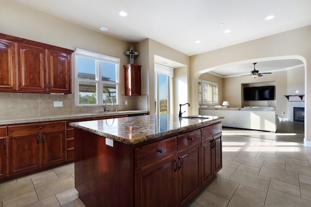 kitchen with an island with sink, ceiling fan, tasteful backsplash, and sink