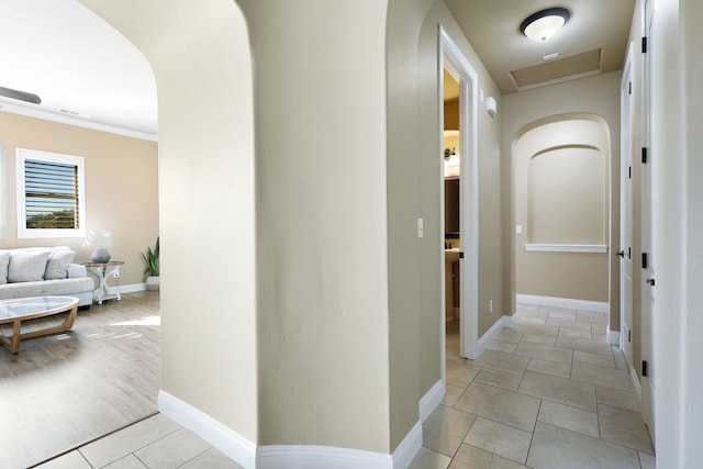 corridor featuring light tile patterned floors and ornamental molding