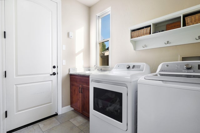 laundry room with sink, washing machine and clothes dryer, and cabinets