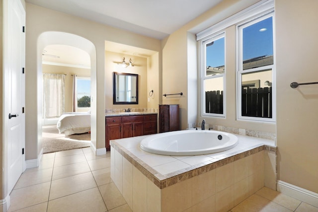 bathroom with ornamental molding, tiled tub, vanity, and tile patterned floors