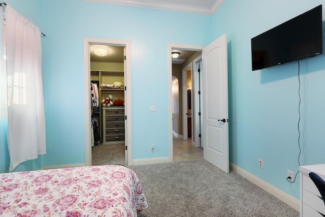 bedroom with ornamental molding, light colored carpet, a closet, and a walk in closet