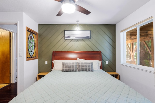 bedroom with ceiling fan, wood walls, and wood-type flooring