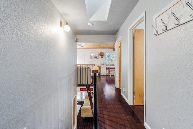 30570 Sleepy Hollow Dr, Shingletown, CA 96088 - hall featuring a textured wall, dark wood-style flooring, an upstairs landing, and a skylight