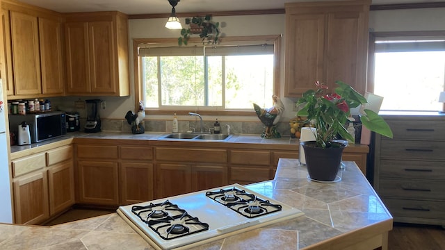 kitchen featuring white gas stovetop, crown molding, sink, tile counters, and decorative light fixtures