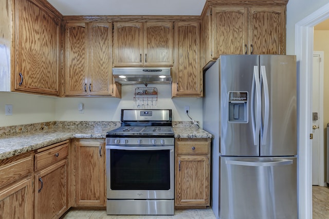 kitchen featuring appliances with stainless steel finishes, light tile patterned flooring, and light stone countertops