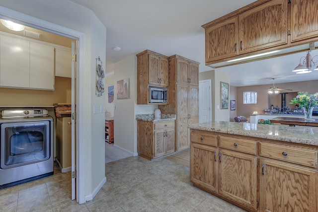 kitchen featuring washer / dryer, ceiling fan, stainless steel microwave, and light stone counters