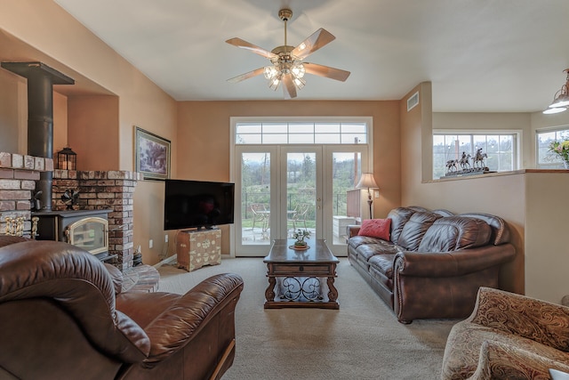 living room featuring ceiling fan, light colored carpet, and a wood stove