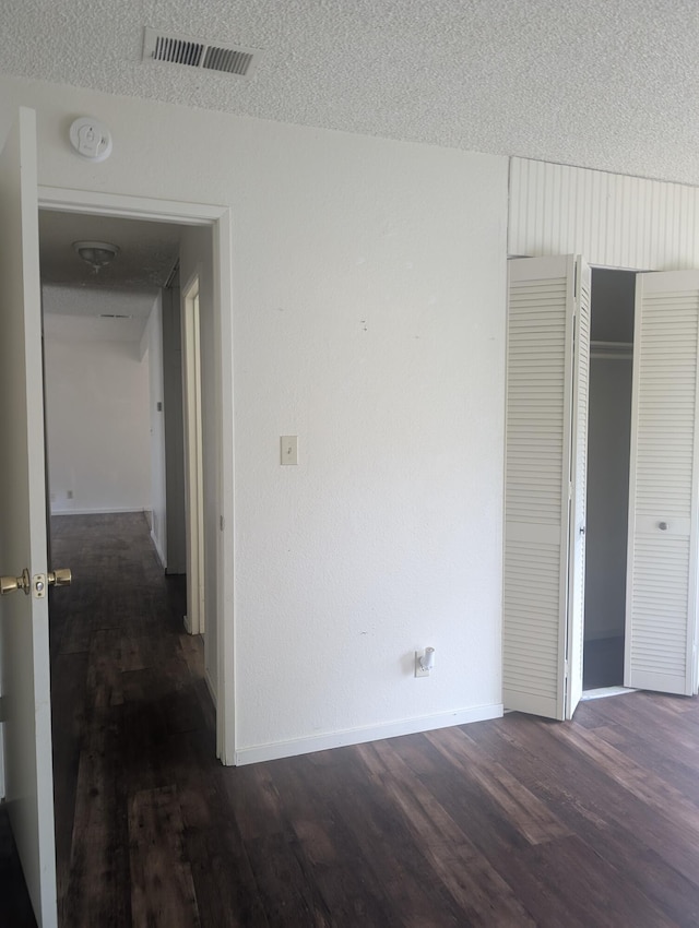 interior space with a closet, dark hardwood / wood-style flooring, and a textured ceiling