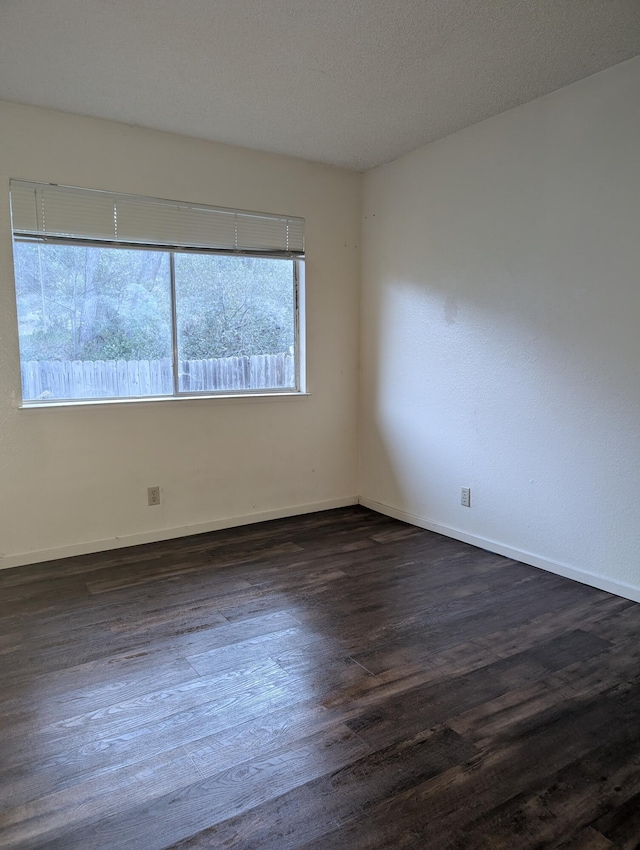 spare room with a textured ceiling and dark hardwood / wood-style floors