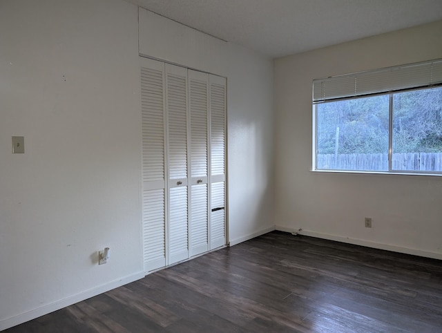 unfurnished bedroom with a closet and dark wood-type flooring