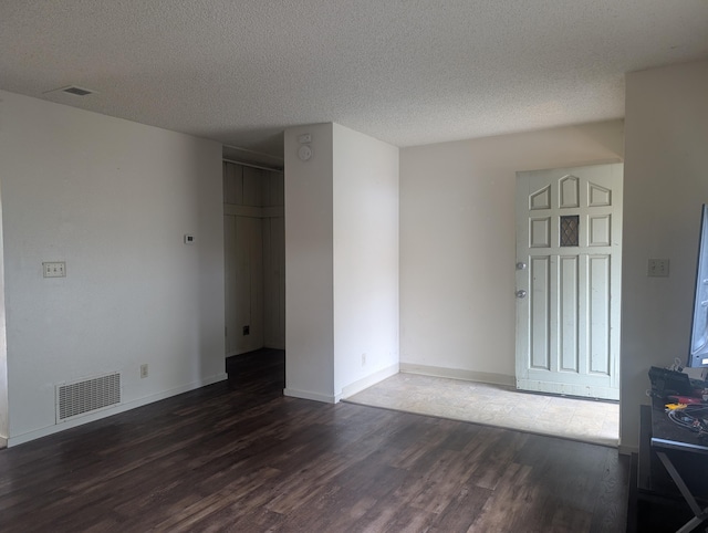 unfurnished room with a textured ceiling and dark hardwood / wood-style floors