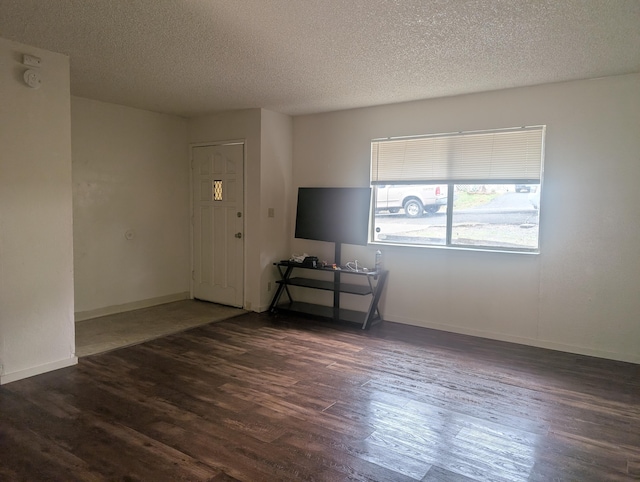 unfurnished living room featuring a textured ceiling and dark hardwood / wood-style floors