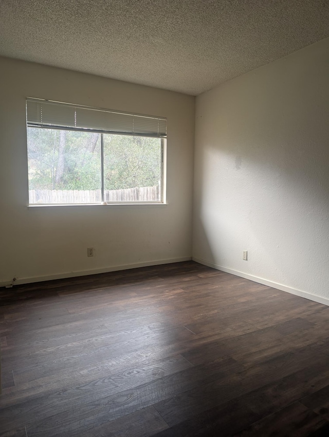 unfurnished room featuring dark wood-type flooring and a textured ceiling