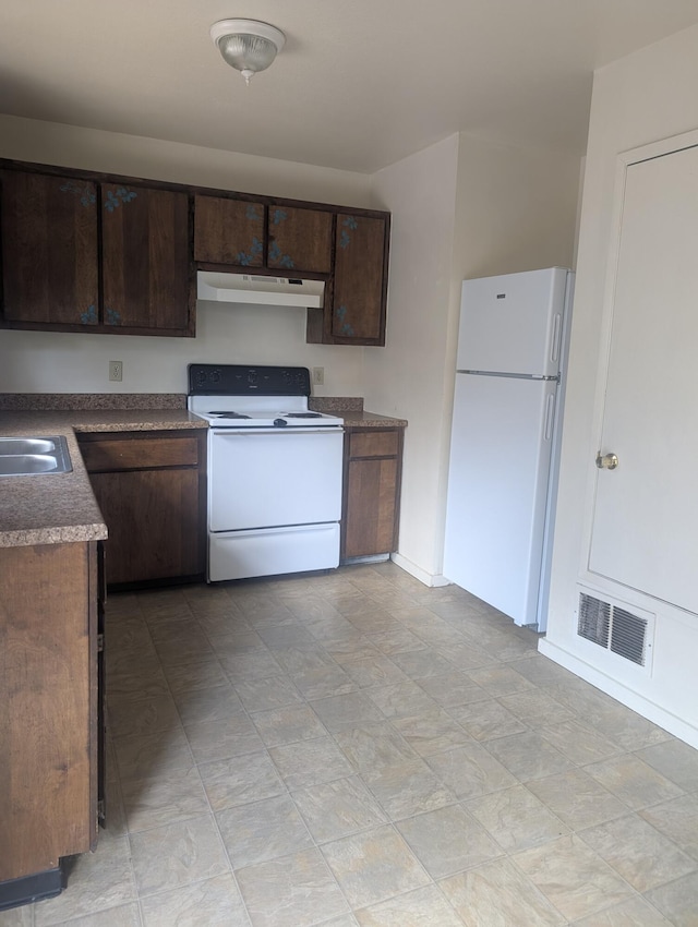 kitchen featuring white appliances, dark brown cabinetry, and sink