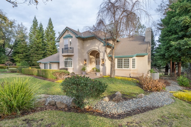 view of front of house featuring a balcony and a front yard