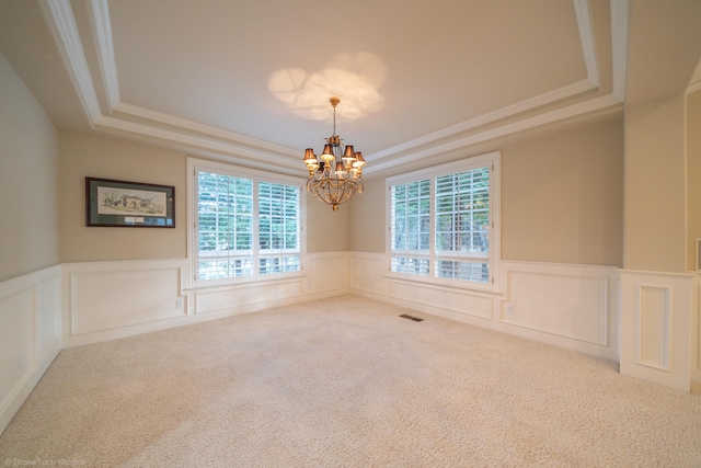 spare room featuring an inviting chandelier, a tray ceiling, crown molding, and carpet flooring