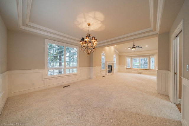 spare room featuring ceiling fan with notable chandelier, ornamental molding, a tray ceiling, and carpet flooring