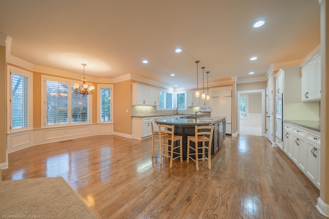 kitchen with a wealth of natural light, white cabinetry, a kitchen island, and crown molding