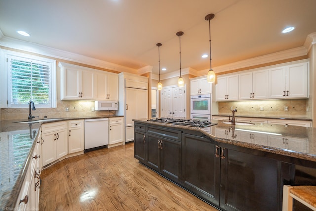 kitchen with white cabinets, white appliances, hanging light fixtures, and sink