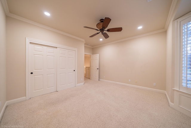 unfurnished bedroom with crown molding, ceiling fan, light carpet, and a closet