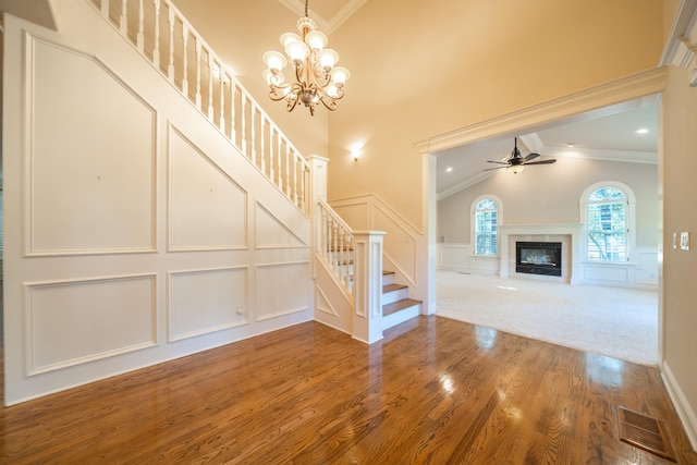 unfurnished living room with ceiling fan with notable chandelier, lofted ceiling, hardwood / wood-style floors, and crown molding